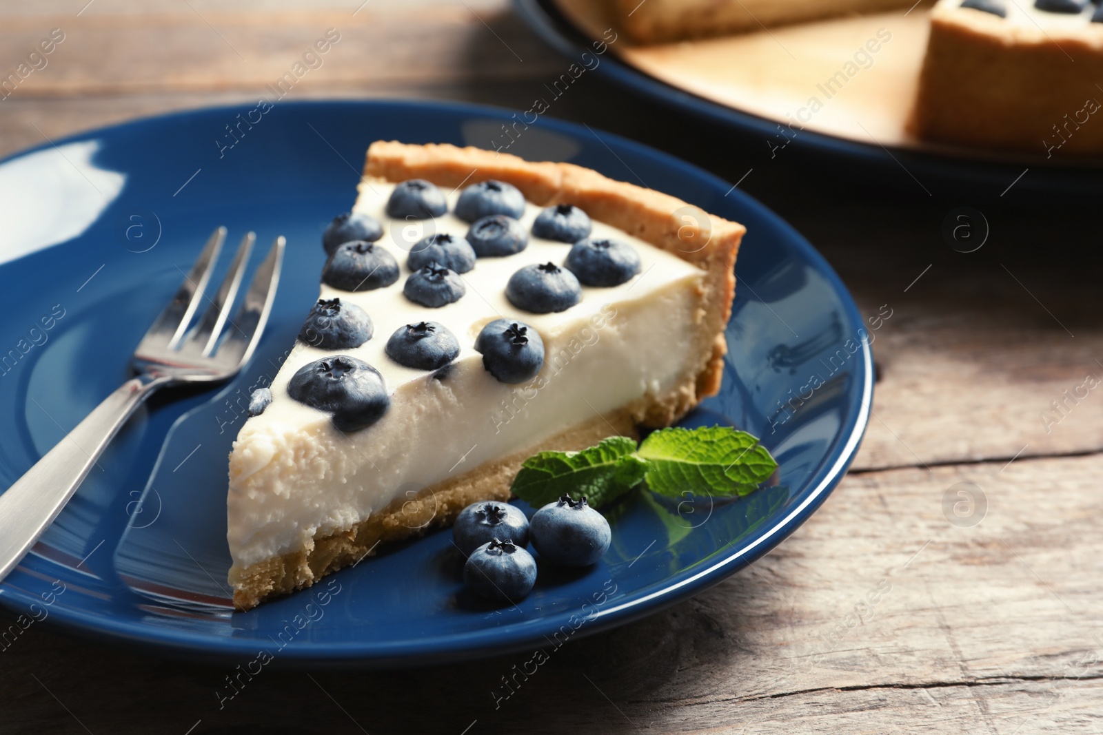 Photo of Plate with piece of tasty blueberry cake on table