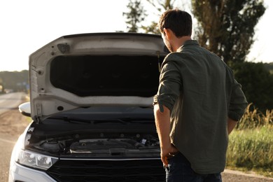 Man near broken car outdoors, back view