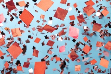 Image of Shiny pink confetti falling down on light blue background