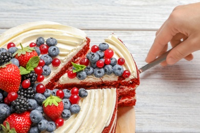 Photo of Woman taking piece of delicious homemade red velvet cake from table, closeup