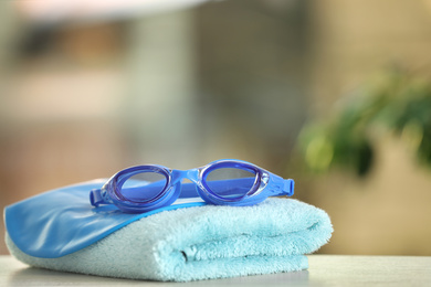 Photo of Swimming cap, goggles and towel against blurred background. Space for text