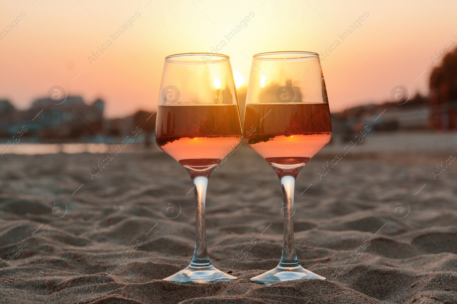 Photo of Glasses of tasty rose wine on sandy beach