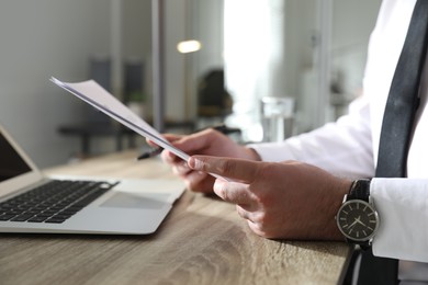 Businessman working with documents at wooden desk in office, closeup