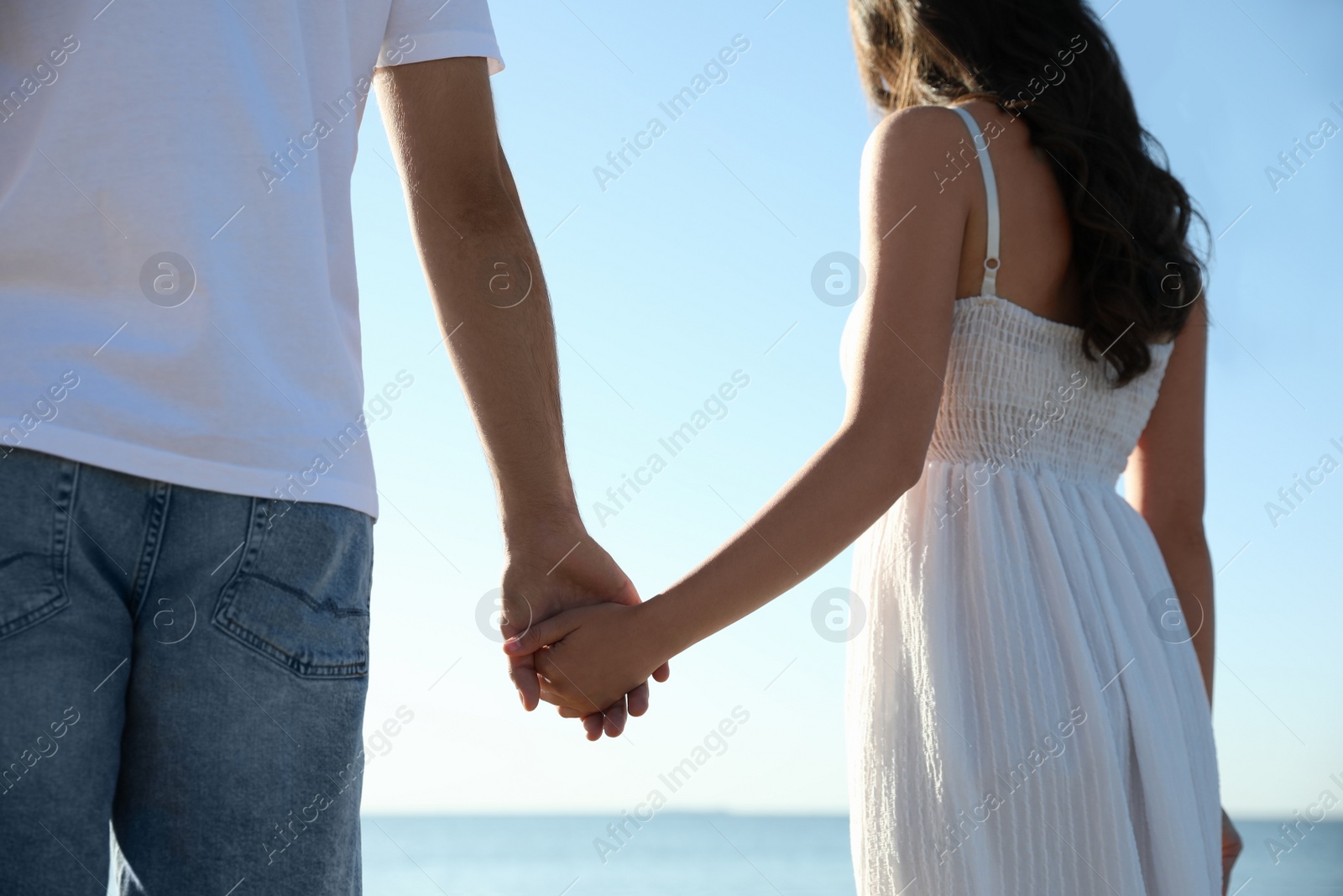 Photo of Young couple walking on beach, closeup. Honeymoon trip