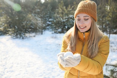 Woman holding snowball outdoors on winter day, space for text