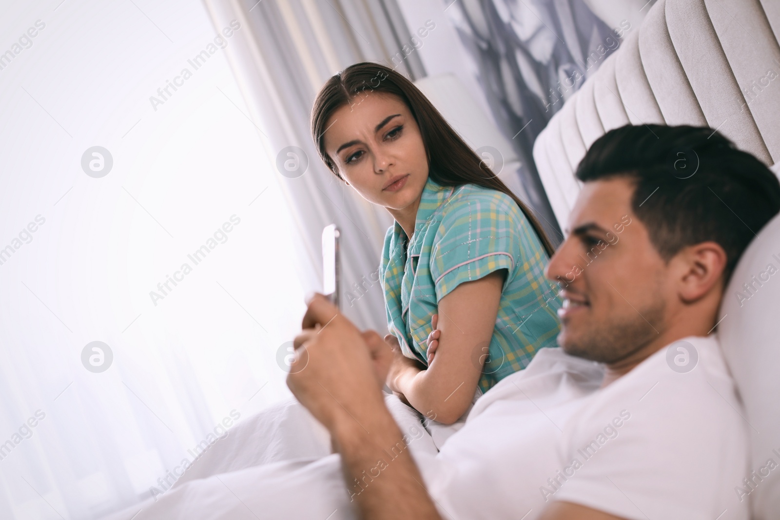 Photo of Man preferring smartphone over spending time with his girlfriend at home. Jealousy in relationship