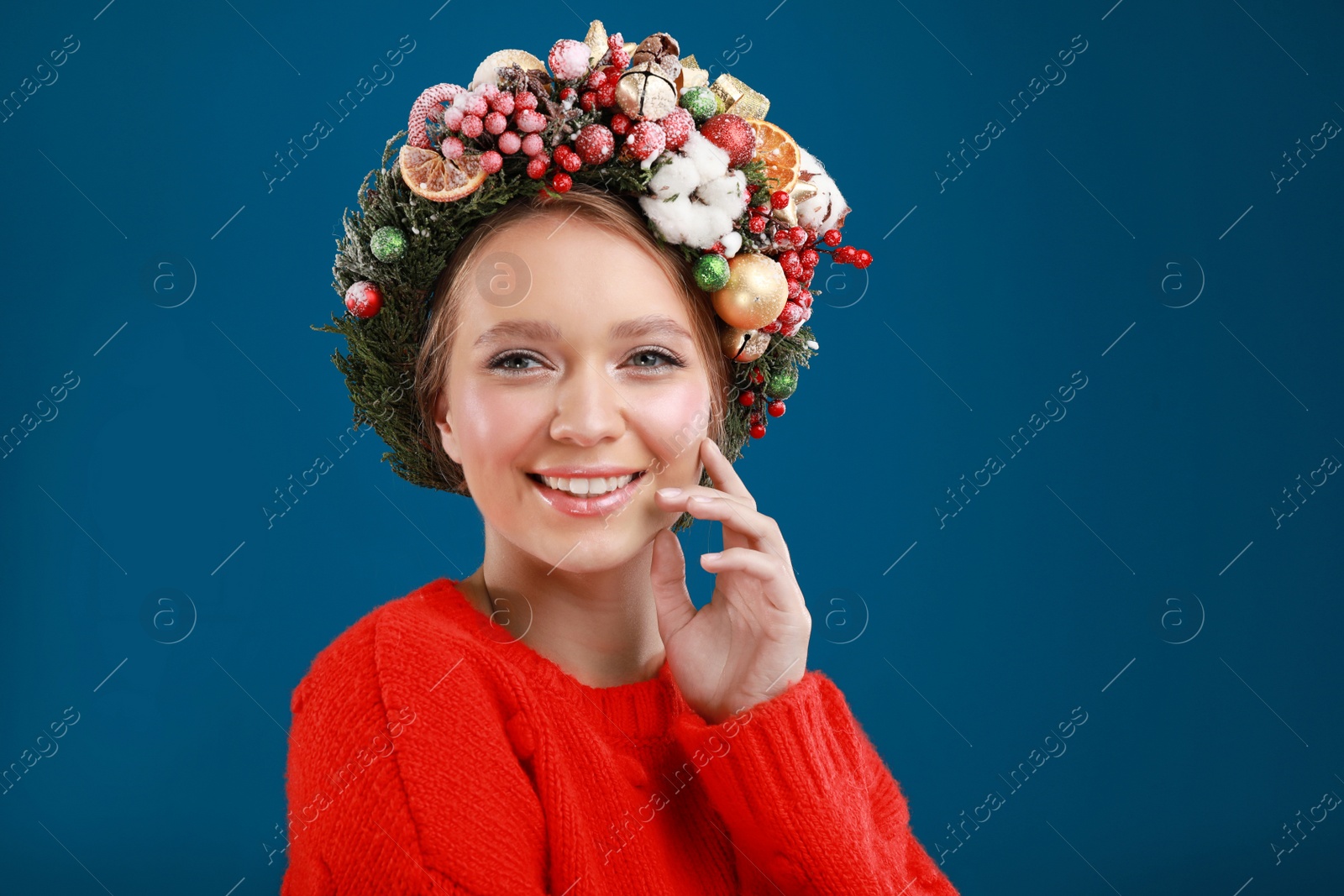 Photo of Beautiful young woman wearing Christmas wreath on blue background