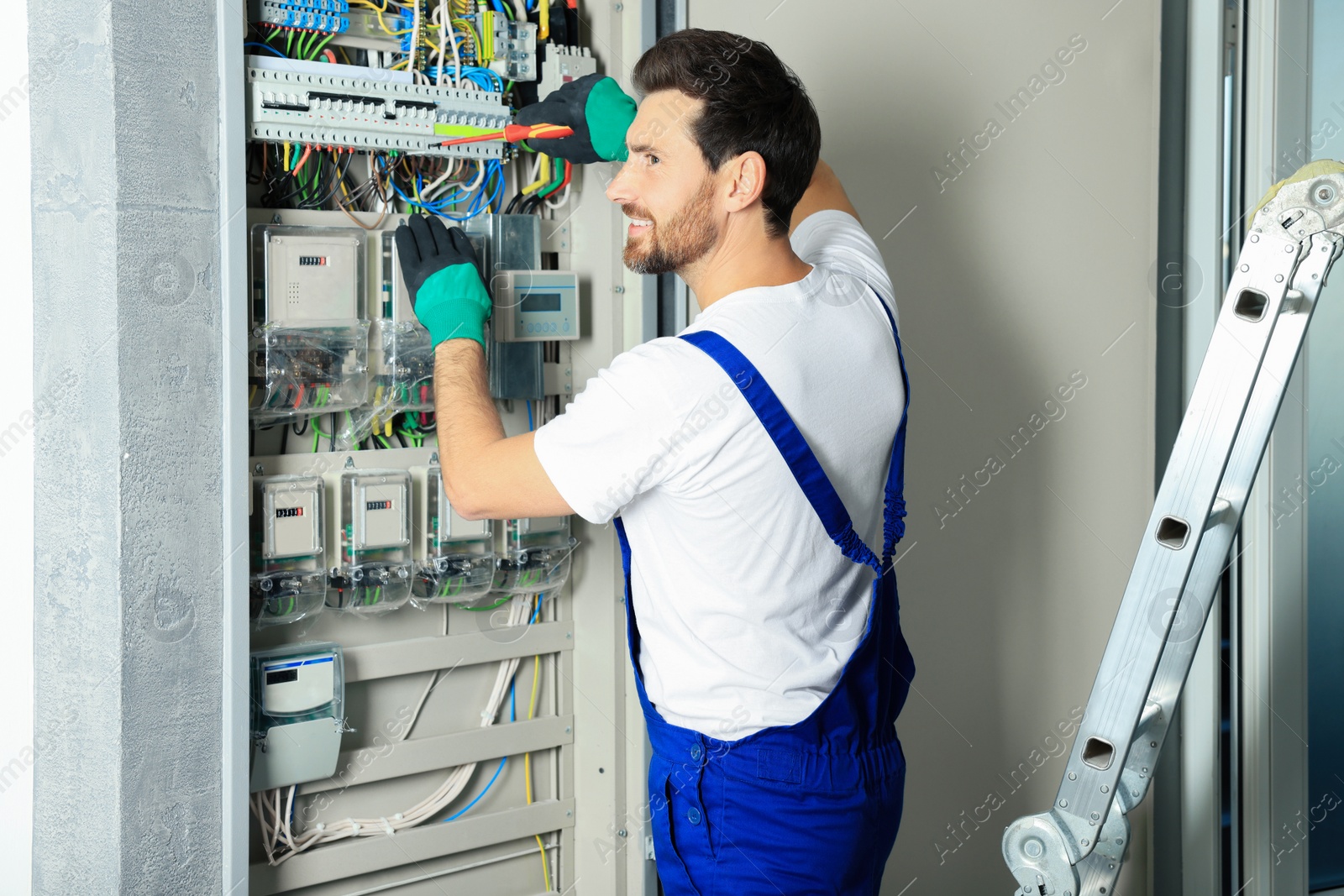 Photo of Electrician repairing fuse box with screwdriver indoors