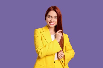 Happy woman with red dyed hair on purple background