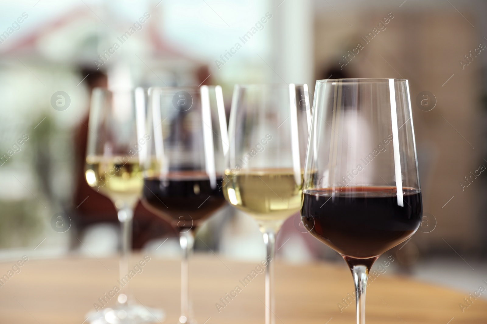 Photo of Glasses with different wines on table against blurred background