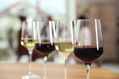 Glasses with different wines on table against blurred background