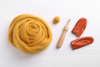 Flat lay composition with wool and needle felting tools on white wooden table