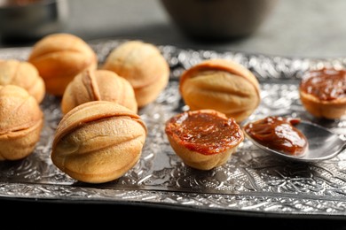 Homemade walnut shaped cookies with boiled condensed milk on vintage metal plate, closeup