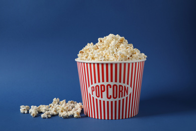 Photo of Delicious popcorn in paper bucket on blue background