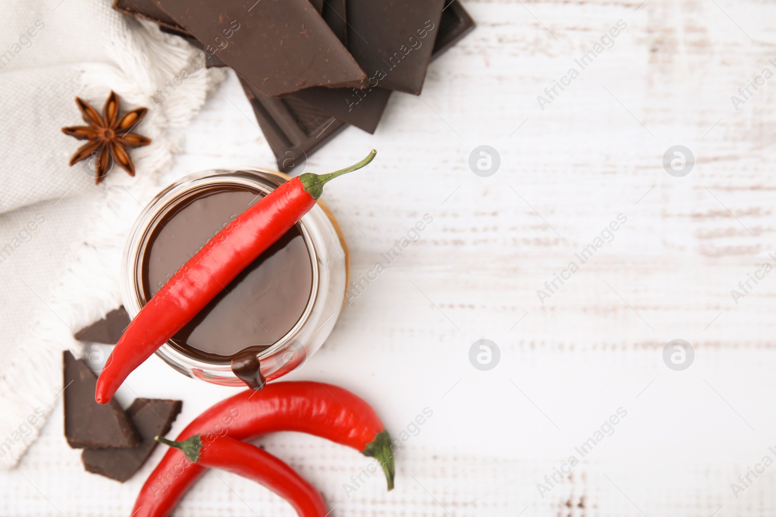 Photo of Glass of hot chocolate with chili pepper on white wooden table, flat lay. Space for text