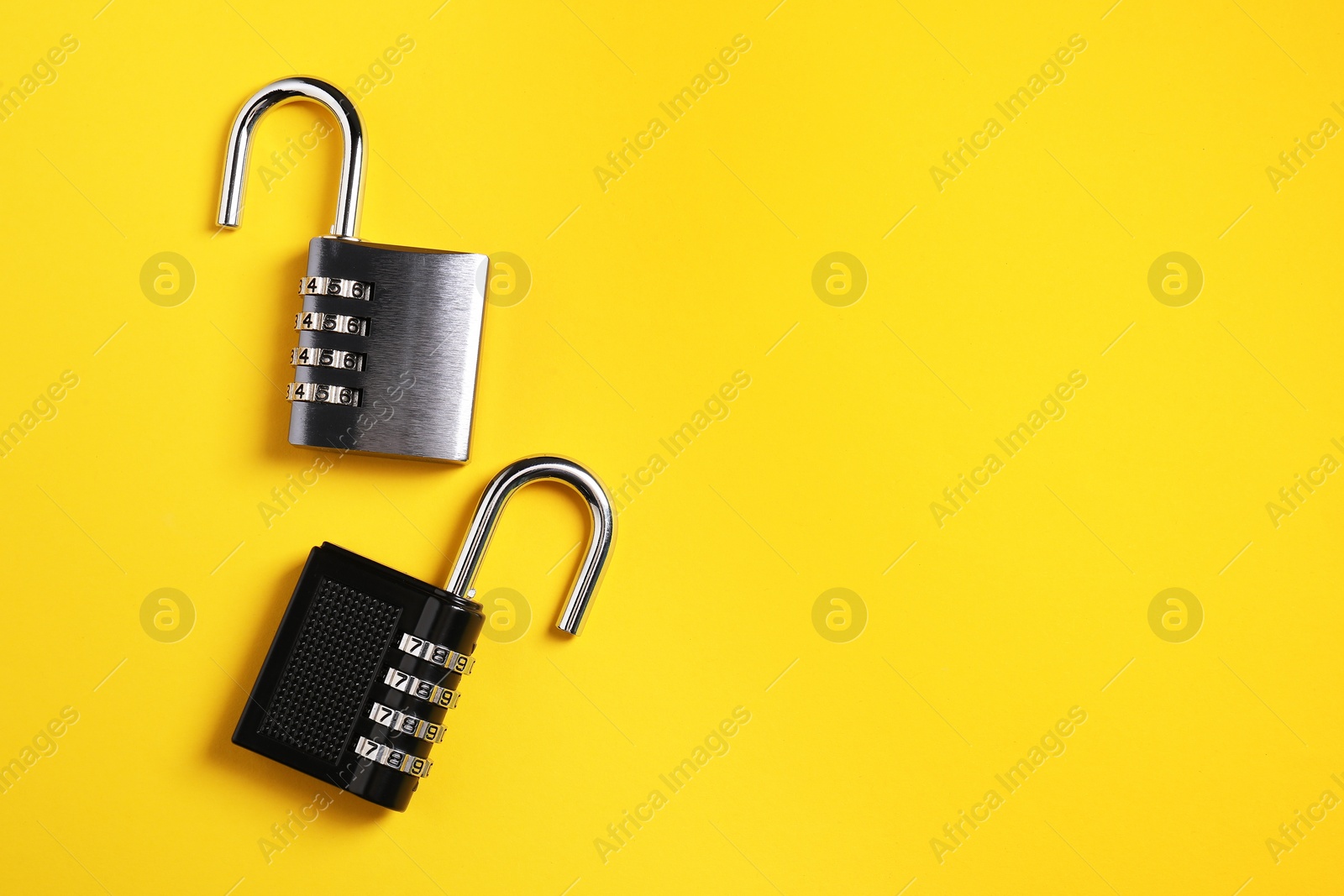 Photo of Steel combination padlocks on yellow background, top view. Space for text