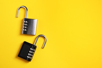 Steel combination padlocks on yellow background, top view. Space for text