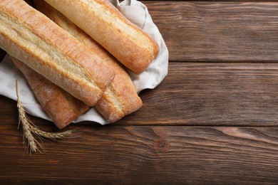 Photo of Different tasty baguettes and spikelets on wooden table, flat lay. Space for text