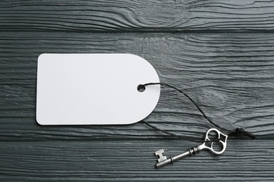 Photo of Key with blank tag on grey wooden table, top view. Keyword concept