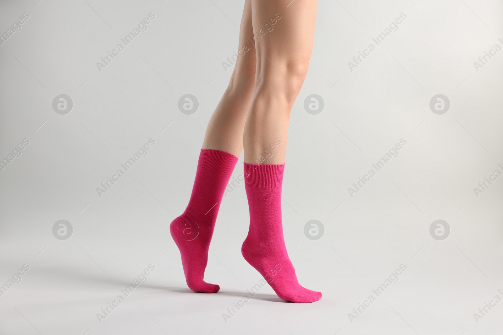 Photo of Woman in stylish bright pink socks on light grey background, closeup