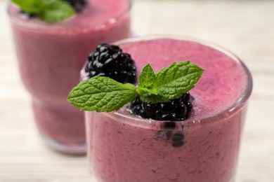 Photo of Glass of blackberry smoothie with mint and berries on light table, closeup