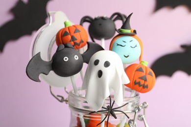 Photo of Delicious Halloween themed cake pops on pink background, closeup
