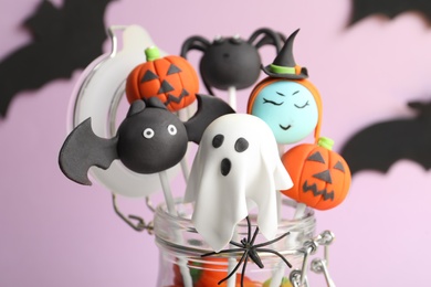 Delicious Halloween themed cake pops on pink background, closeup