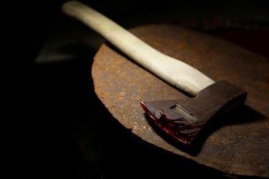 Axe with blood on rusty metal surface, closeup. Space for text