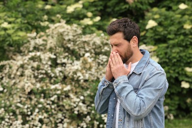 Photo of Man suffering from seasonal pollen allergy on spring day, space for text