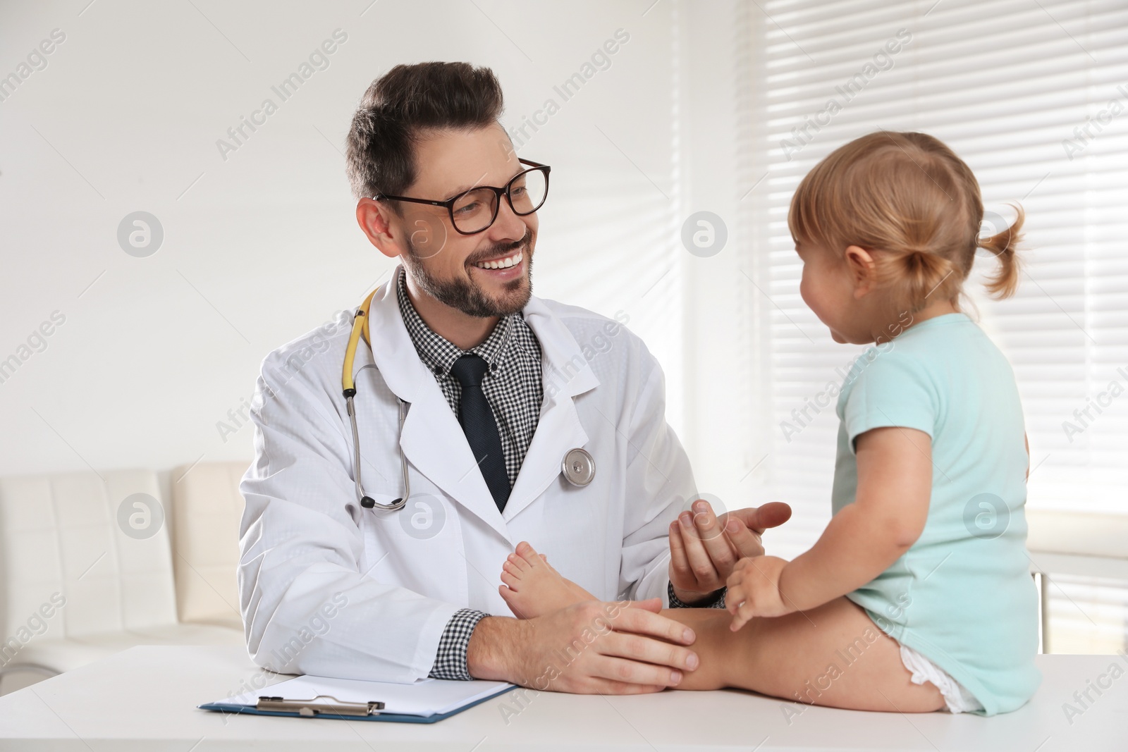 Photo of Pediatrician examining cute little baby in clinic