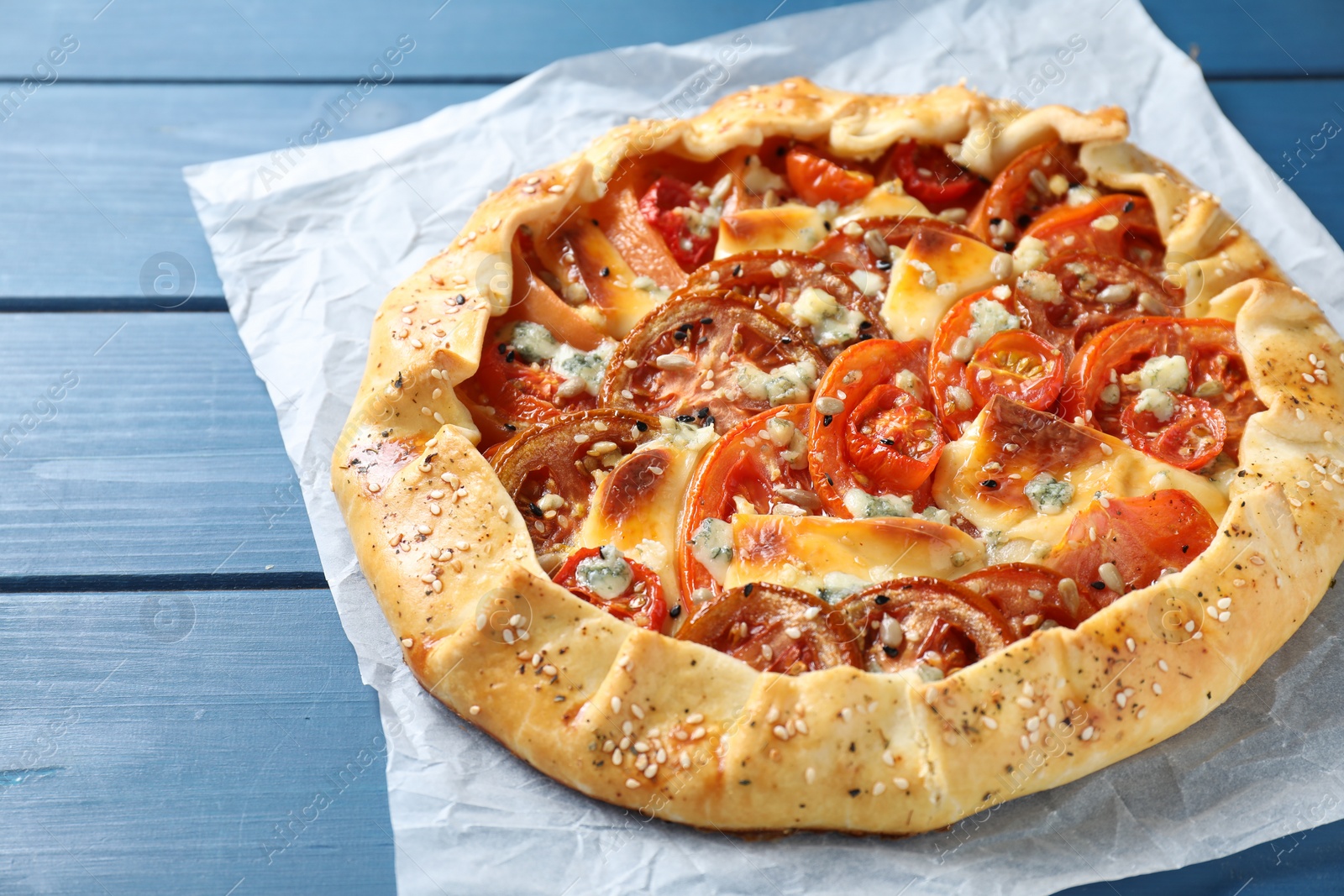 Photo of Tasty galette with tomato and cheese (Caprese galette) on blue wooden table, closeup