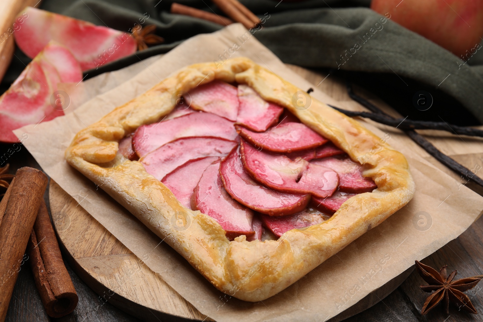 Photo of Delicious galette with apples, spices and fruit on wooden table, closeup