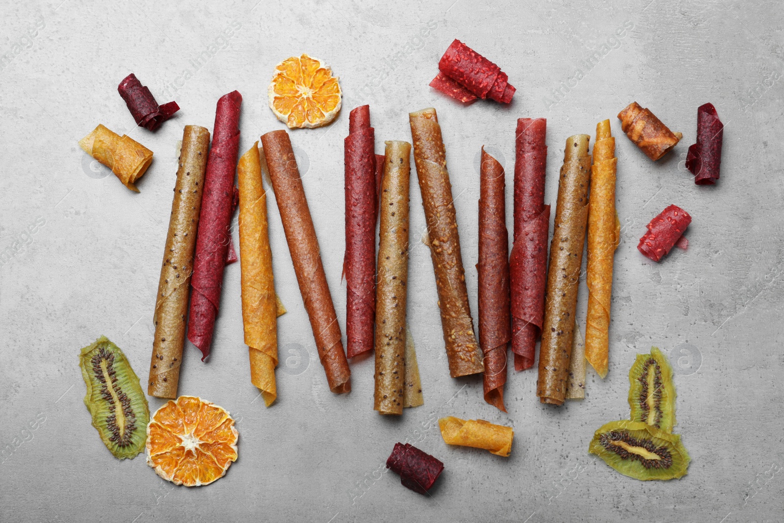 Photo of Delicious fruit leather rolls on grey table, flat lay