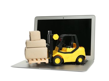 Photo of Laptop, toy forklift with wooden pallet and boxes on white background