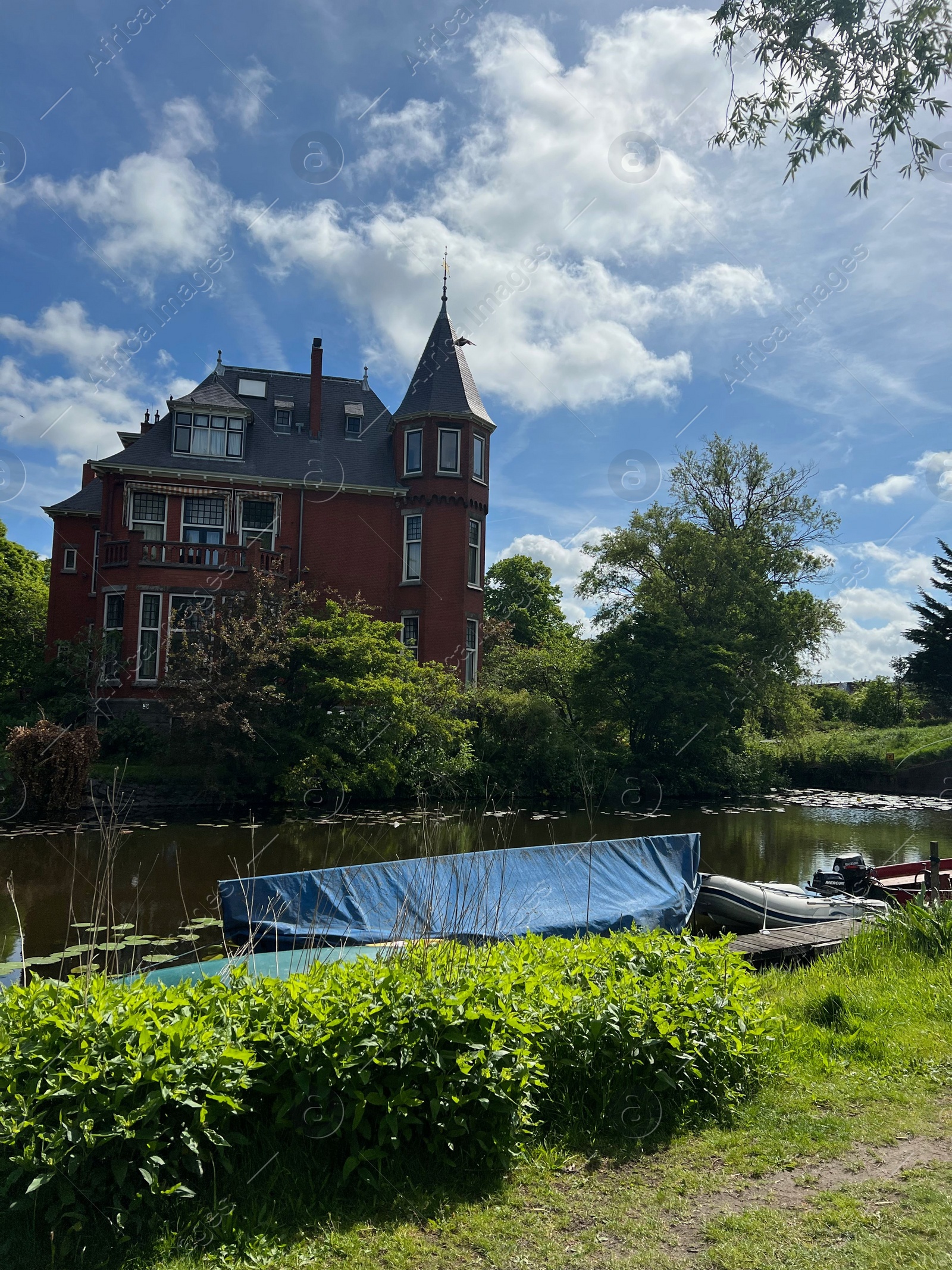Photo of Beautiful view of house near river with moored boat on sunny day