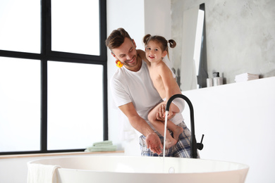 Young father with cute little daughter in bathroom