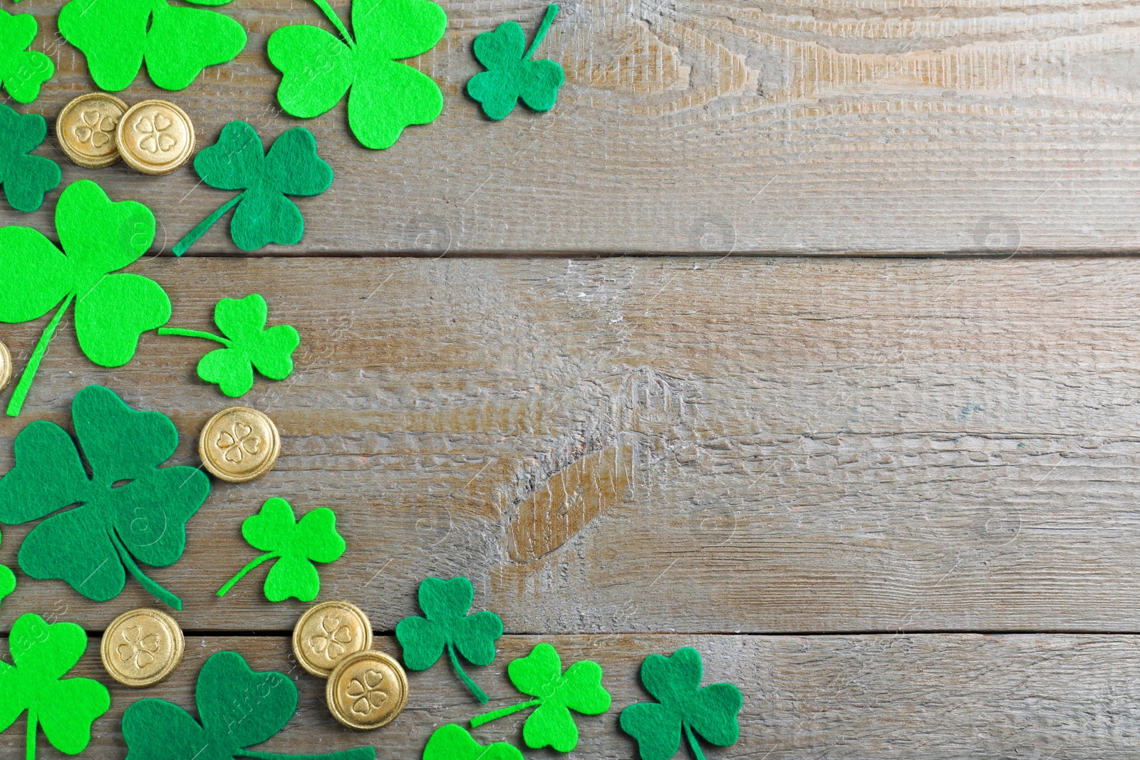 Photo of Flat lay composition with clover leaves and gold coins on wooden table, space for text. St. Patrick's Day celebration