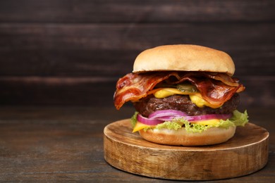 Photo of Tasty burger with bacon, vegetables and patty on wooden table, space for text