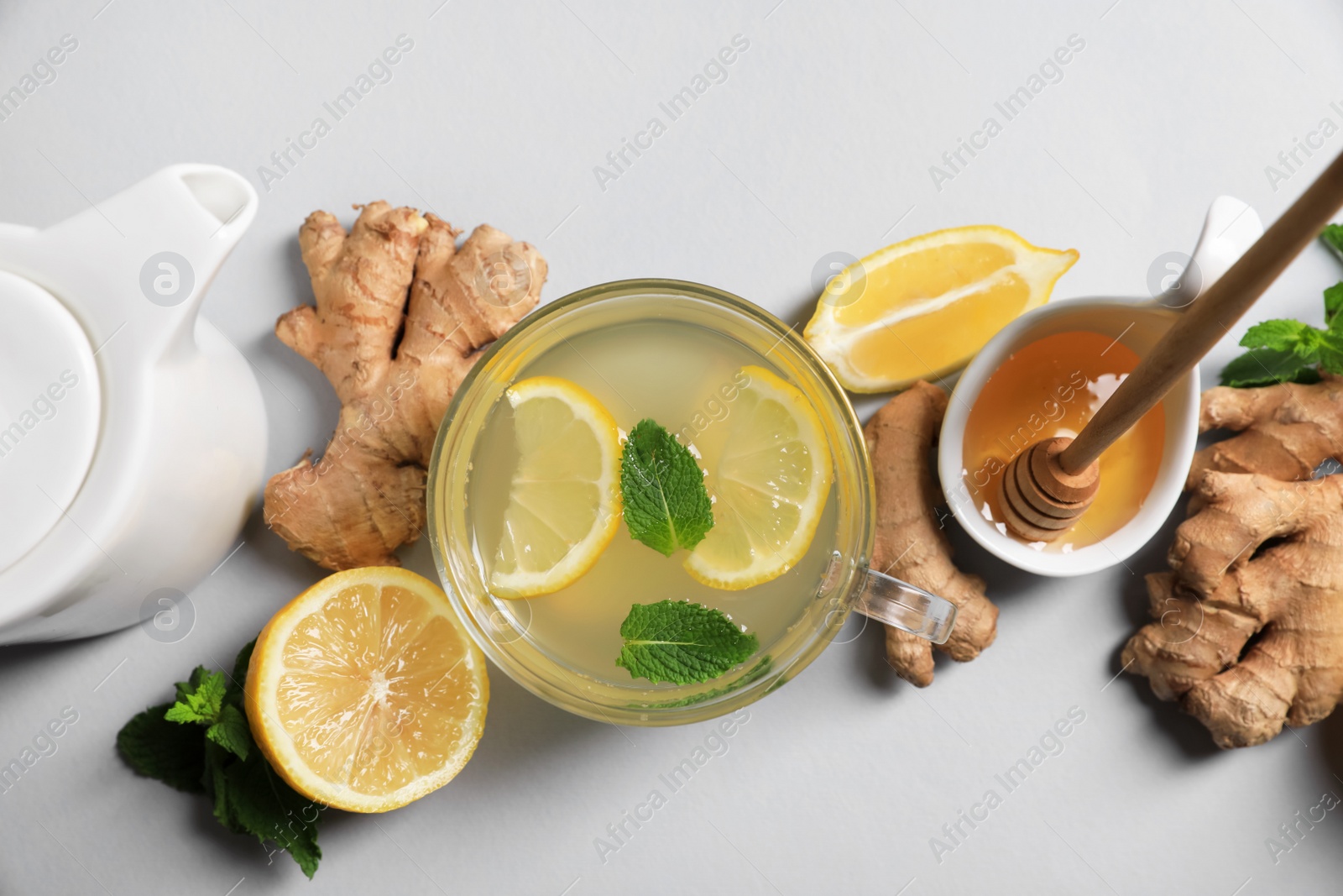 Photo of Delicious ginger tea and ingredients on light grey background, flat lay