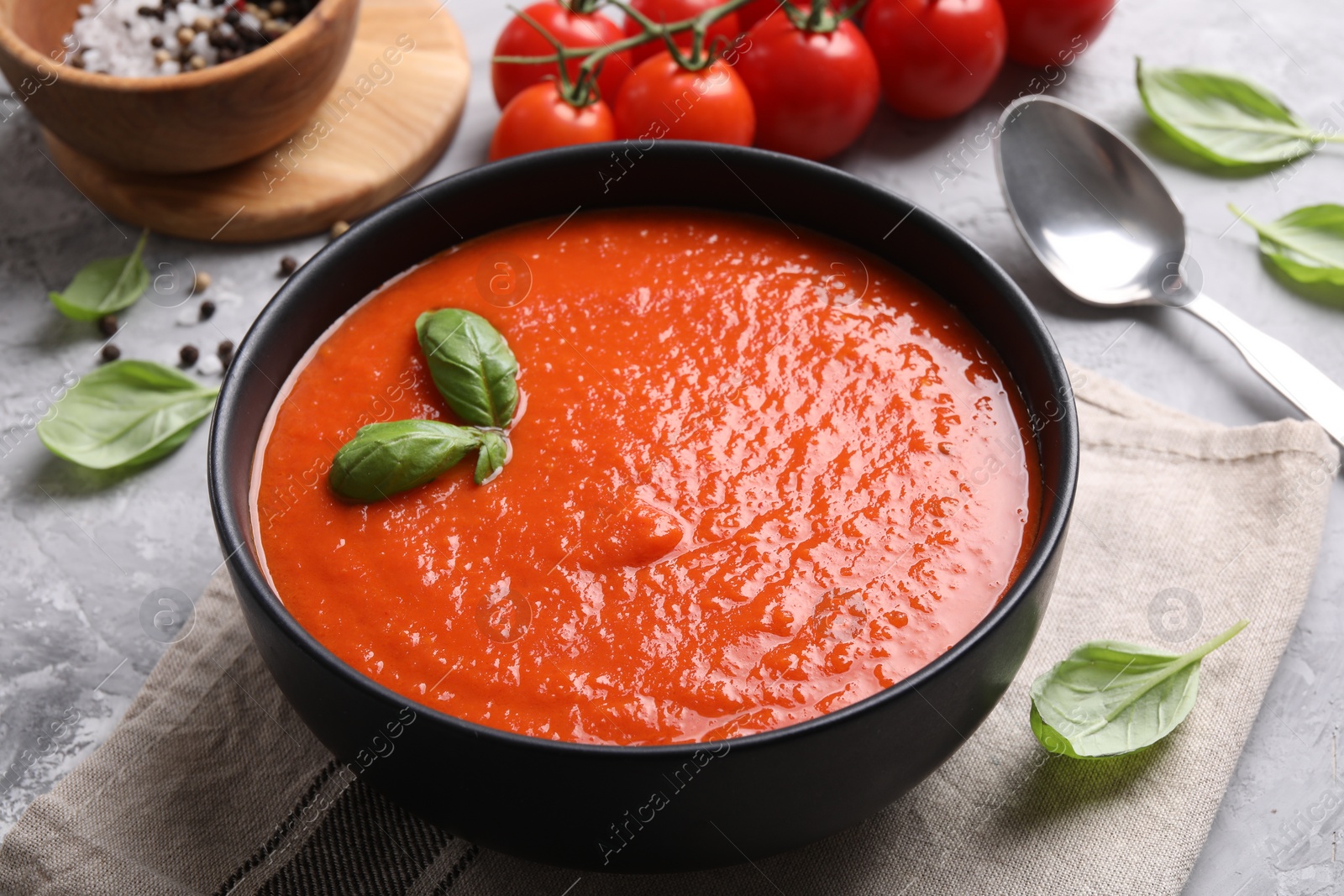 Photo of Delicious tomato cream soup served on grey textured table, closeup