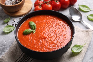 Photo of Delicious tomato cream soup served on grey textured table, closeup