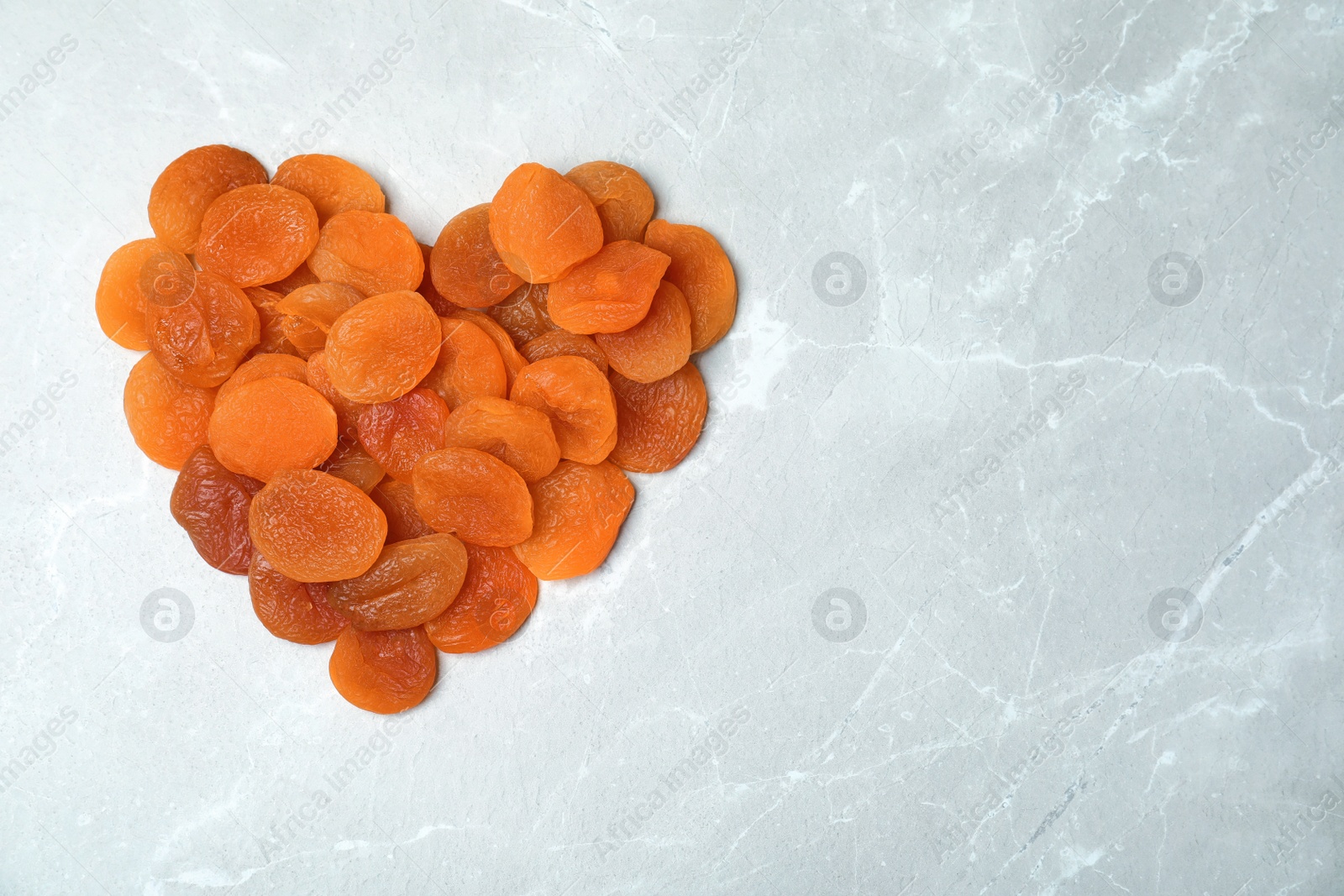 Photo of Heart made of apricots on grey background, top view with space for text. Dried fruit as healthy food
