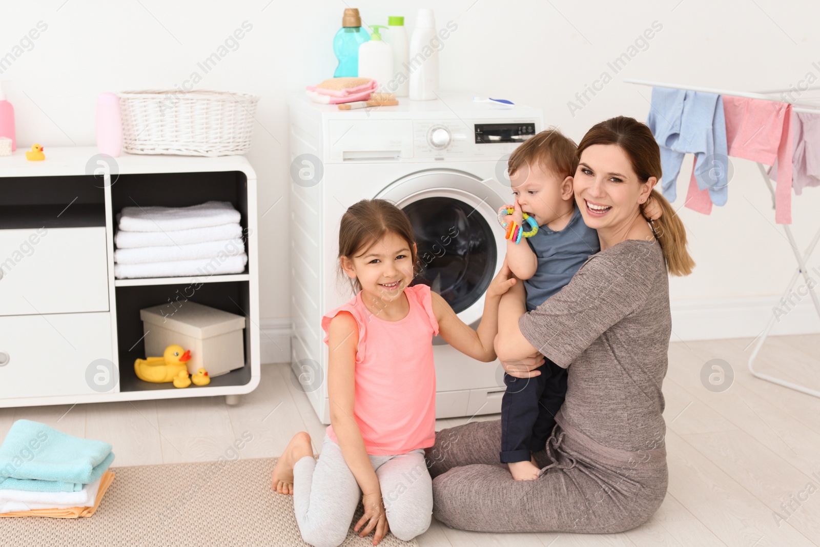 Photo of Housewife with little children in laundry room