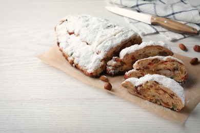 Photo of Traditional Christmas Stollen with icing sugar on white wooden table, space for text