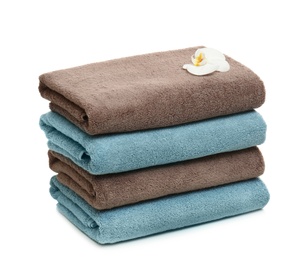 Stack of clean folded towels with flower on white background