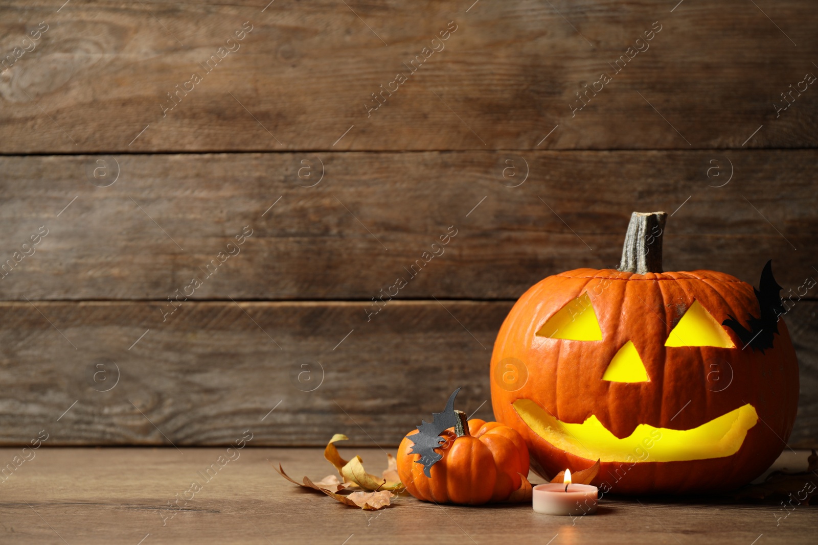 Photo of Composition with carved pumpkin and Halloween decor on wooden table, space for text