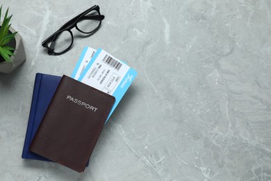 Photo of Flat lay composition with tickets, passport and glasses on light grey marble table, space for text. Business trip
