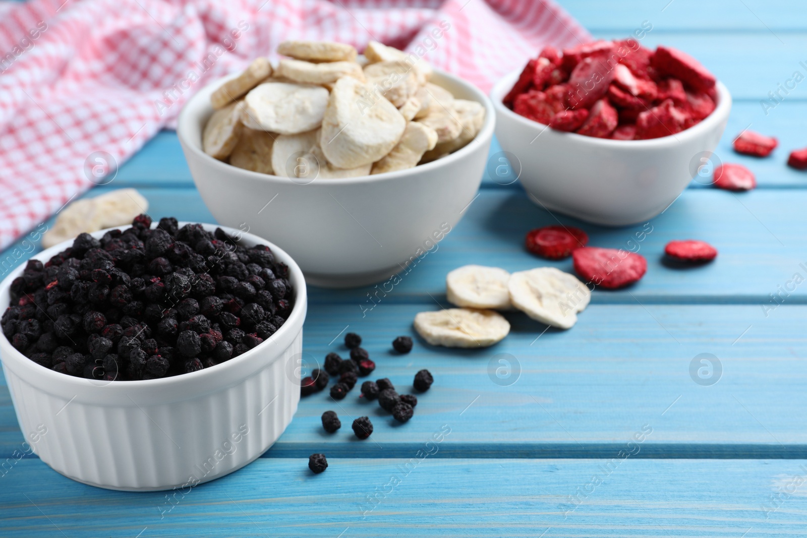 Photo of Bowls and dried fruits on turquoise wooden table