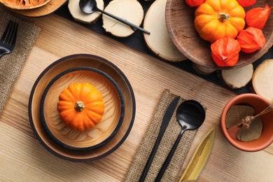 Photo of Autumn table setting with pumpkins on wooden background, flat lay
