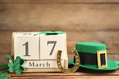 Photo of Composition with leprechaun hat and block calendar on wooden background. St Patrick's Day celebration